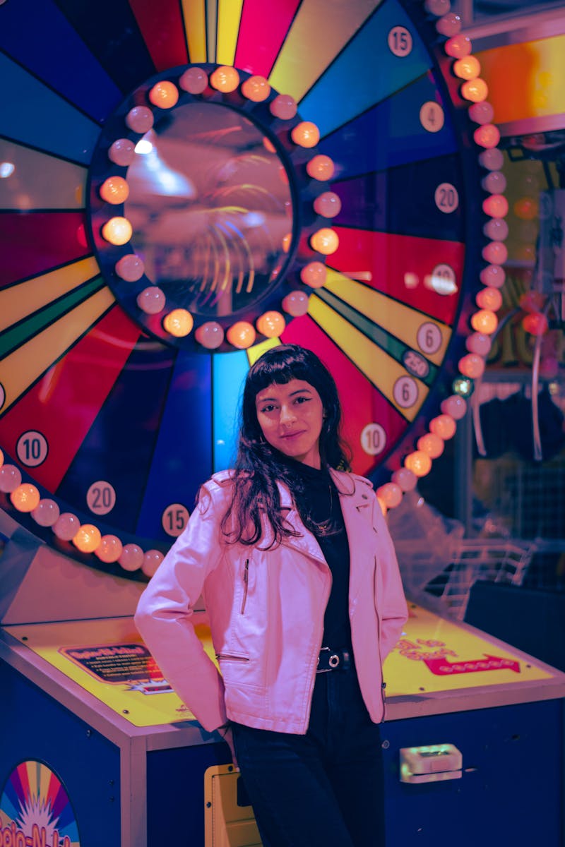 Posed Photo of a Woman in a Pink Jacket Standing next to a Wheel of Fortune